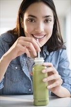 Hispanic woman drinking green juice