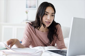 Hispanic woman paying bills on laptop