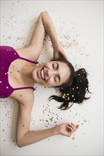 Hispanic woman laying in confetti