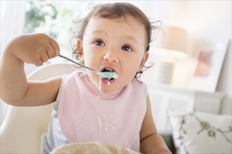 Mixed race baby girl eating yogurt
