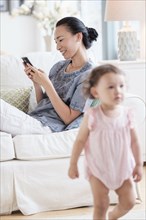 Mother with cell phone ignoring baby daughter