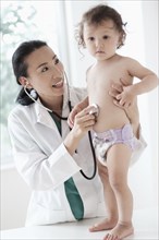 Doctor listening to stomach of baby girl