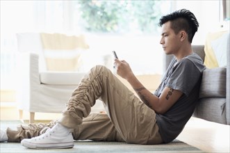 Asian man using cell phone in living room