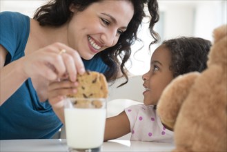 Mother and daughter eating milk and cookies