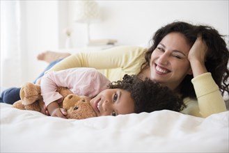 Mother and daughter smiling on bed