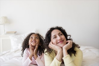 Mother and daughter daydreaming on bed