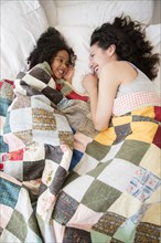 Mother and daughter laughing on bed