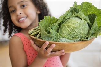 Mixed race girl holding bowl of vegetables