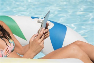 Caucasian woman using digital tablet in swimming pool