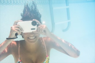 Caucasian woman using underwater camera in swimming pool