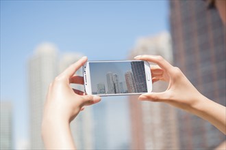 Hispanic woman photographing skyline with cell phone