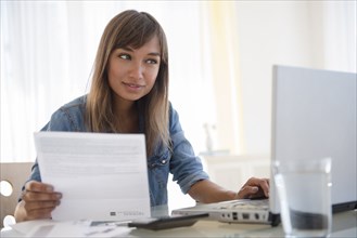 Mixed race woman paying bills on laptop