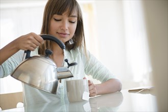 Mixed race woman pouring cup of tea
