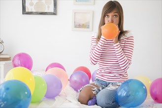 Mixed race woman blowing up balloons