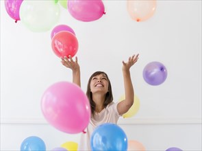 Mixed race woman playing with balloons