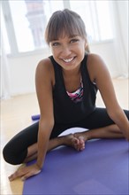 Mixed race woman stretching on yoga mat