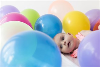 Caucasian baby girl laying in balloons