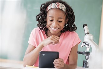 Black student using digital tablet in science class