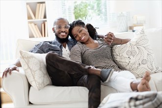 Black couple smiling on sofa