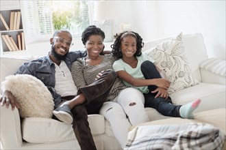 Black family smiling on sofa