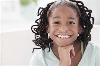 Smiling Black girl resting chin in hand