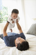 Father holding baby son on bed