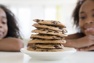 Mixed race sisters admiring stack of cookies