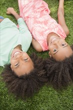 Mixed race sisters laying in grass