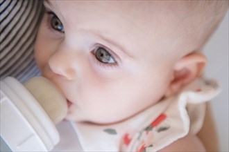 Caucasian mother feeding baby daughter