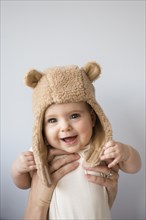 Caucasian mother holding baby daughter in fuzzy hat