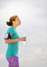 Mixed race runner drinking water outdoors