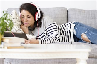 Mixed race woman listening to headphones on sofa