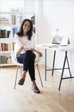 Mixed race businesswoman smiling in home office