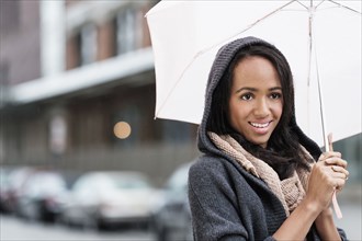 Mixed race woman carrying umbrella outdoors