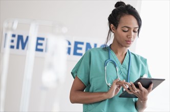 Mixed race nurse using digital tablet in hospital