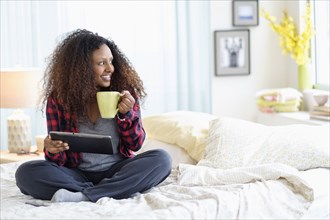 Black woman using digital tablet on bed