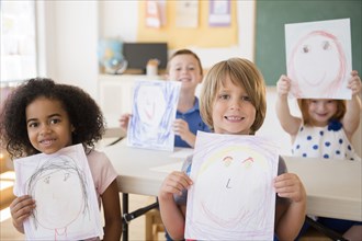 Students showing drawings in classroom
