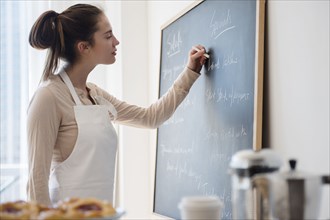 Native American woman writing on specials board in cafe