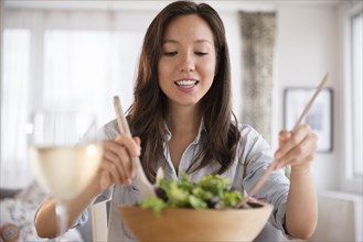 Mixed race woman tossing salad