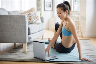 Mixed race woman doing yoga video in living room