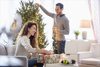 Couple decorating for Christmas in living room