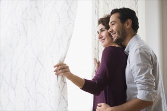 Couple looking out window curtain