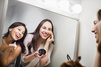 Women applying makeup in mirror
