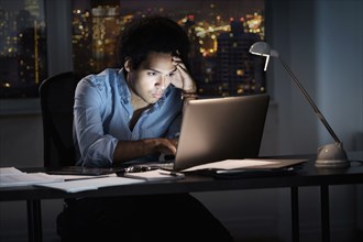 Mixed race businessman working late in office