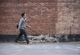 Mixed race man walking near brick wall
