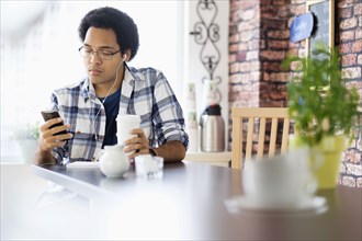 Mixed race man using cell phone in coffee shop