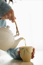 Hispanic woman pouring cup of tea
