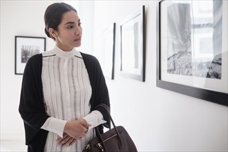 Hispanic woman admiring art in gallery