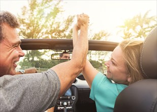 Caucasian couple holding hands in convertible