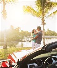 Caucasian couple hugging near convertible